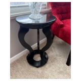 black accent table featuring a distinctive curved base and a round top. 