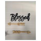 wall decor featuring a black scripted "Blessed" sign and two wooden arrow accents. 