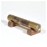 STEPHEN AUGER BRASS KALEIDOSCOPE WITH WOODEN STAND | Textured brass cylinder kaleidoscope, signed wi