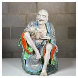 Chinese Porcelain Elder Figure | A laughing Luohan (or Buddhist immortal) seated and holding a bell,