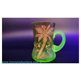 A green uranium glass souvenir mug with hand-painted gold palm tree and applied handle, measuring 3.