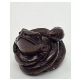 A carved wooden netsuke-style figure of a frog entwined with a snake, signed on the underside and me