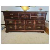 Wooden dresser with brass handles and decorative carving; measures 63 x 18 x 32.5"