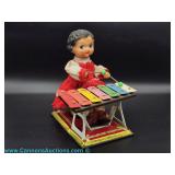  Tin wind-up toy of a girl playing a xylophone with a red dress and lace trim from the late 20th cen