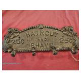 Cast iron wall-mounted coat rack with decorative scrollwork and raised lettering reading "Haircut an