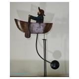 Indonesian AM metal kinetic sculpture of a seated figure rowing a boat on a tall stand with counterw