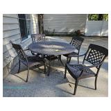 Wrought iron round glass-top patio table and four matching wrought iron chairs with slat seats and s