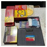 assortment of tools, including drill bits, a pressure tester, and hardware kits 