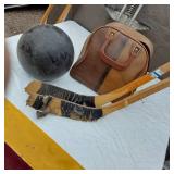 Vintage sports equipment lot including Brunswick Black Beauty and AXIS bowling balls, Pogo stick, hockey sticks, and additional items.