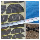 Solar panel with camping gear including BBQ grill, cot, and table