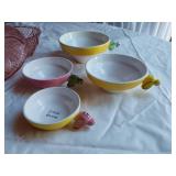 Vintage kitchenware set including Menschik-Goldman measuring cups, pink Depression glass bowls, and floral glass mugs