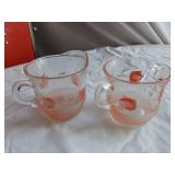 Vintage kitchenware set including Menschik-Goldman measuring cups, pink Depression glass bowls, and floral glass mugs