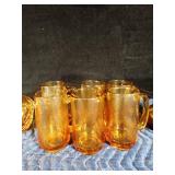 Gold colored glass pitcher, 6 mugs, small drinking glass and 1 brown pitcher