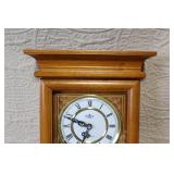 Wall Mount Pendulum Clock with Oak Finish and Roman Numeral Dial