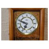 Wall Mount Pendulum Clock with Oak Finish and Roman Numeral Dial