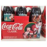 Collection of Vintage Coca-Cola Bottles with Holiday Labels and Wooden Crate