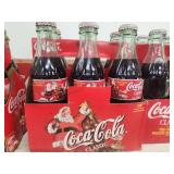 Collection of Vintage Coca-Cola Bottles with Holiday Labels and Wooden Crate