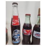 Collection of Vintage Coca-Cola Bottles with Holiday Labels and Wooden Crate