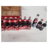 Collection of Vintage Coca-Cola Bottles with Holiday Labels and Wooden Crate
