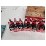 Collection of Vintage Coca-Cola Bottles with Holiday Labels and Wooden Crate