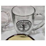 Assorted mugs and glasses including Kimball MN glass mug, Lutsen Glass, Oakley National Bank, Budweiser mugs, and various commemorative mugs