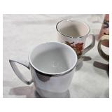 Assorted mugs and glasses including Kimball MN glass mug, Lutsen Glass, Oakley National Bank, Budweiser mugs, and various commemorative mugs