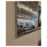 A Silver Framed Beveled Mirror with Rivet Accents.