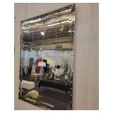 A Silver Framed Beveled Mirror with Rivet Accents.