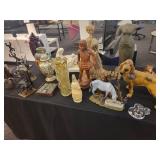 A table full of decor items, animal figures, pottery, glassware, bookends, candle holders, dolls etc.