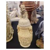 A table full of decor items, animal figures, pottery, glassware, bookends, candle holders, dolls etc.