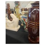 A table full of decor items, animal figures, pottery, glassware, bookends, candle holders, dolls etc.