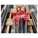 Black pipe bars with red pipe clamps that have swing handles