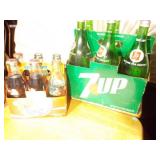 several bottles of 7UP soda in a vintage-style green cardboard carrier.