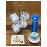 Collection of Vintage Kitchenware Including Federal Glass Mugs, Italian Trivet, Shenango Cup and Saucer, and Blue Thermos