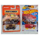 Hot Wheels and Matchbox Die-Cast Vehicles Collection featuring models such as the Hot Wheels "Quick Bite," "Hiway Hauler 2," "Ultimate T-Rex Transporter," and the Matchbox "MBX Self-Driving Bus."