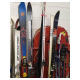 Lots of snow skis, poles down hill and cross country