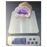 A mesmerizing deep amethyst portal, showcasing rich violet crystals that form a natural, glowing window into the stone’s heart. On a custom wooden stand.