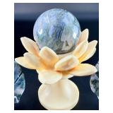 A serene moss agate collection featuring two hand-carved leaf-shaped pieces and a polished sphere with a druzy center resting on a lotus stand.