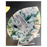 A serene moss agate collection featuring two hand-carved leaf-shaped pieces and a polished sphere with a druzy center resting on a lotus stand.