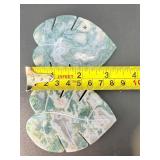 A serene moss agate collection featuring two hand-carved leaf-shaped pieces and a polished sphere with a druzy center resting on a lotus stand.