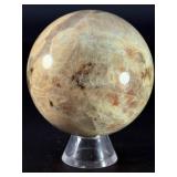 Moonstone Sphere with Blue Flashes is a captivating crystal sphere known for its soft, luminous glow and stunning blue flashes that shimmer as the light moves across its surface.
