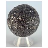 Chiseled Obsidian Sphere is a bold and captivating crystal sphere sculpted from natural obsidian. Its smooth, polished surface is enhanced with subtle chiseled facets, creating depth, texture, and a d