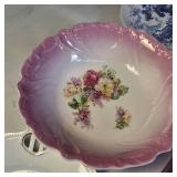 Collection of vintage porcelain and glass dishes, featuring various floral patterns, gilded rims, and crystal designs.