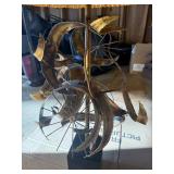 This Lot is a 1970s Hollywood Regency-style table lamp, featuring a sculpted metal base and a pleated shade