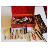 Red metal toolbox with assorted hand tools and accessories including pliers, screwdrivers, a utility knife, and a socket set
