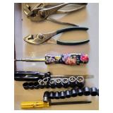 Red metal toolbox with assorted hand tools and accessories including pliers, screwdrivers, a utility knife, and a socket set