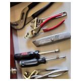 Red metal toolbox with assorted hand tools and accessories including pliers, screwdrivers, a utility knife, and a socket set
