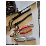 Red metal toolbox with assorted hand tools and accessories including pliers, screwdrivers, a utility knife, and a socket set