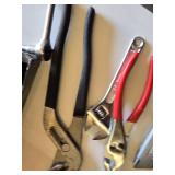 Red metal toolbox with assorted hand tools and accessories including pliers, screwdrivers, a utility knife, and a socket set