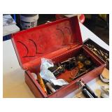 Red metal toolbox with assorted hand tools and accessories including pliers, screwdrivers, a utility knife, and a socket set